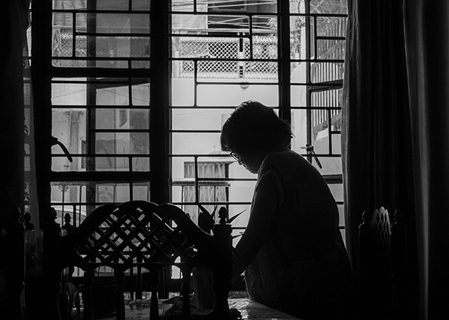 A woman clearing a table in a darkening house.